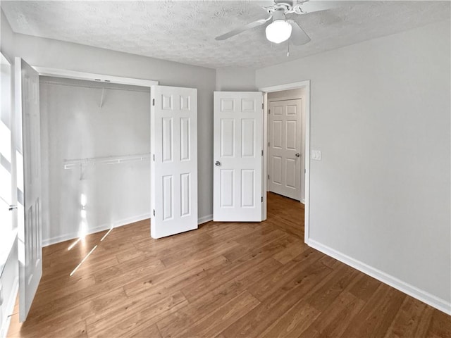 3968 Oak Glenn Dr, Duluth, GA 30096 - unfurnished bedroom featuring wood finished floors, baseboards, a closet, a textured ceiling, and a ceiling fan