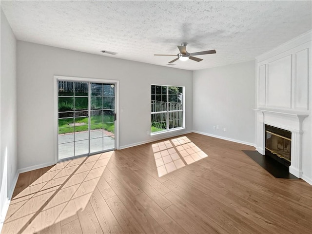 3968 Oak Glenn Dr, Duluth, GA 30096 - unfurnished living room featuring a ceiling fan, wood finished floors, a fireplace with flush hearth, baseboards, and a textured ceiling