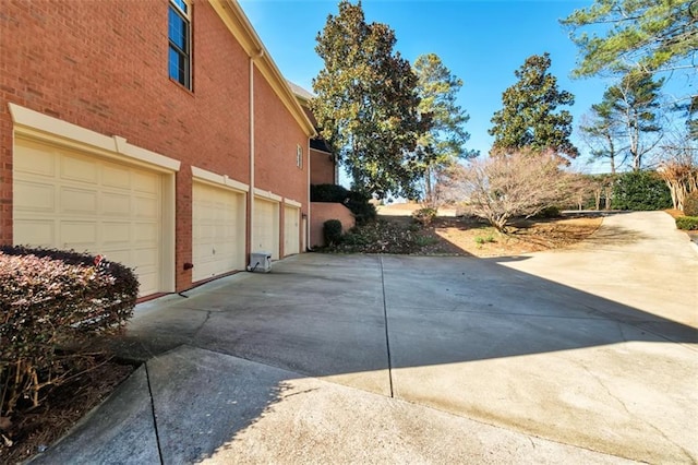 view of side of property featuring concrete driveway, an attached garage, and stucco siding