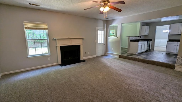3881 Micah Ln, Ellenwood, GA 30294 - unfurnished living room with a ceiling fan, dark colored carpet, a textured ceiling, and a fireplace with flush hearth