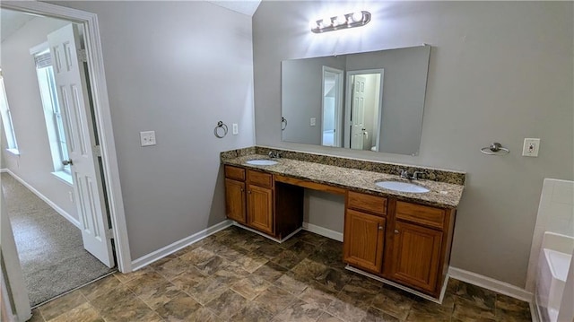 3881 Micah Ln, Ellenwood, GA 30294 - bathroom featuring baseboards, double vanity, a bath, and stone finish flooring