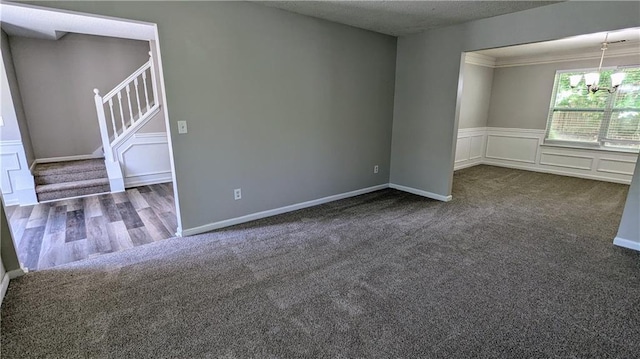 3881 Micah Ln, Ellenwood, GA 30294 - spare room featuring dark colored carpet, a chandelier, stairs, a wainscoted wall, and a decorative wall