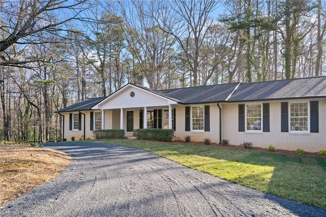 ranch-style home featuring brick siding, driveway, and a front yard