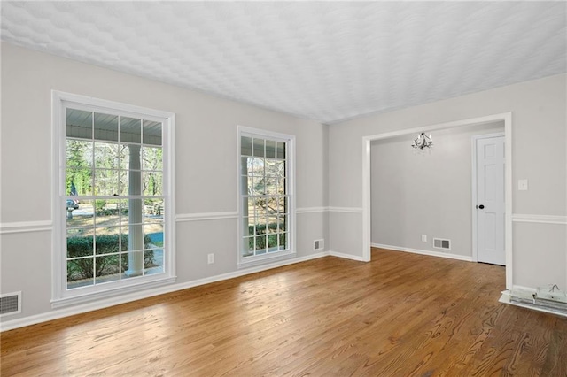 spare room with visible vents, baseboards, and wood finished floors