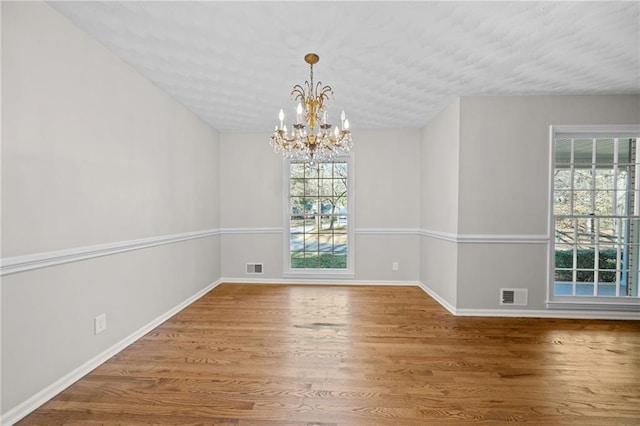 unfurnished dining area with visible vents, plenty of natural light, and wood finished floors