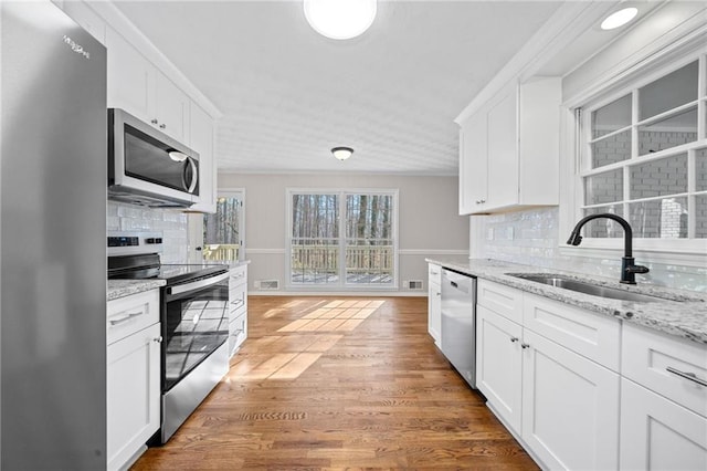 kitchen with a sink, wood finished floors, backsplash, and stainless steel appliances