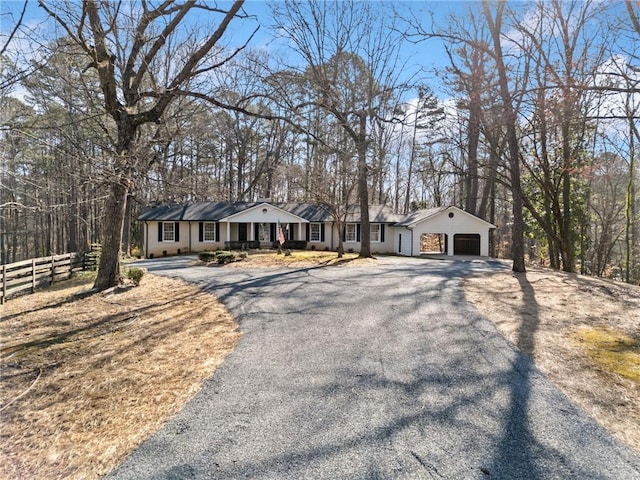 ranch-style house with a garage, a porch, driveway, and fence