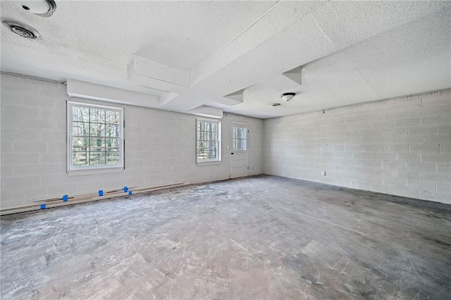 spare room featuring concrete block wall, visible vents, concrete flooring, and a textured ceiling