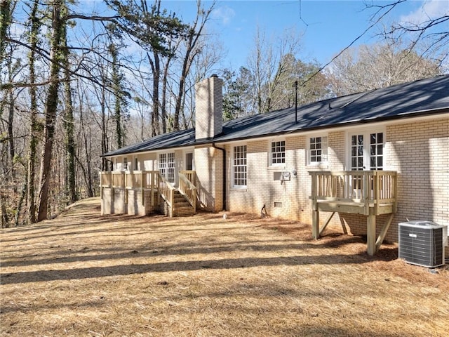 back of house with a wooden deck, central AC, a chimney, french doors, and brick siding