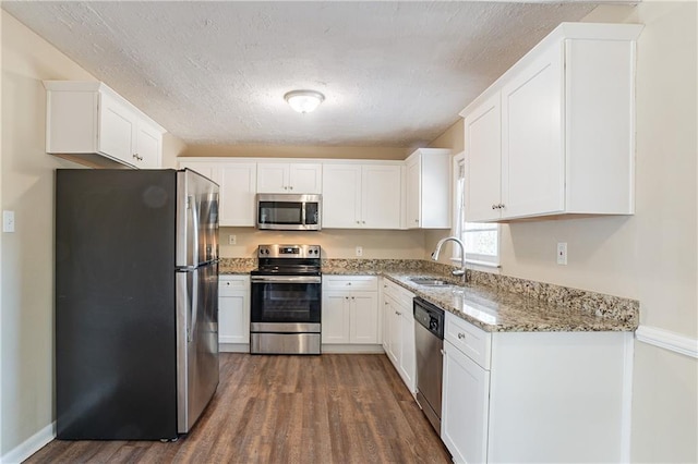 3018 Meadowview Dr SE, Atlanta, GA 30316 - kitchen featuring appliances with stainless steel finishes, sink, white cabinets, dark hardwood / wood-style flooring, and light stone counters