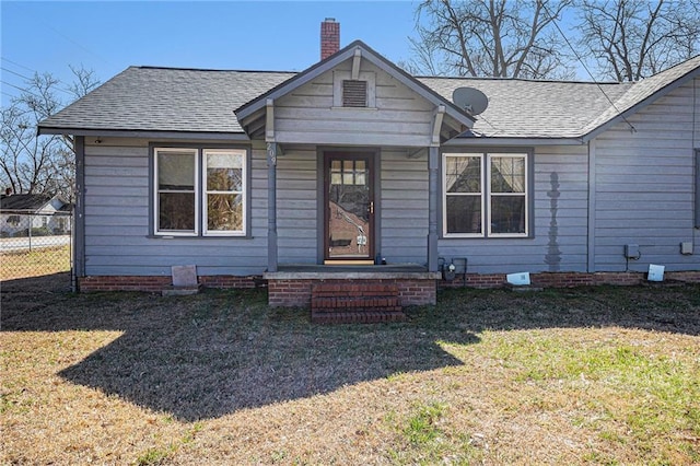 view of front of house with roof with shingles, a chimney, fence, and a front yard