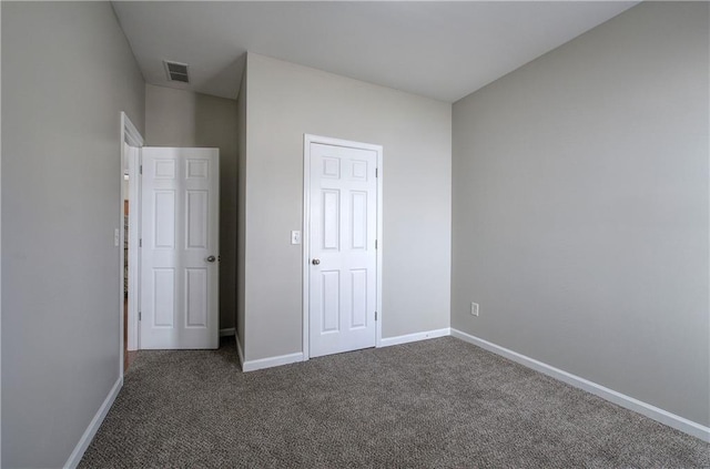 unfurnished bedroom with dark colored carpet and a closet