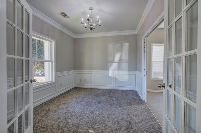 spare room featuring dark carpet, french doors, an inviting chandelier, and crown molding