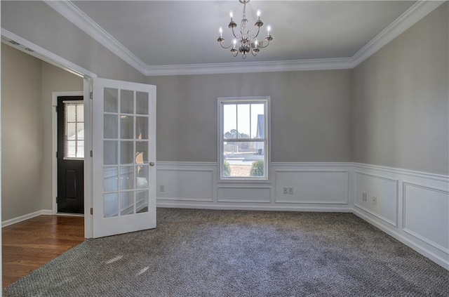 empty room with dark carpet, french doors, ornamental molding, and an inviting chandelier