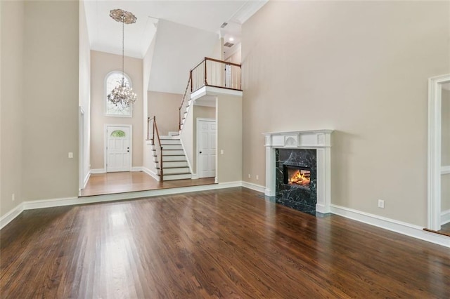 entrance foyer featuring high vaulted ceiling, stairs, dark wood-type flooring, a premium fireplace, and baseboards