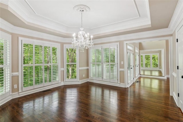 unfurnished dining area with a chandelier, a tray ceiling, plenty of natural light, wood finished floors, and ornamental molding