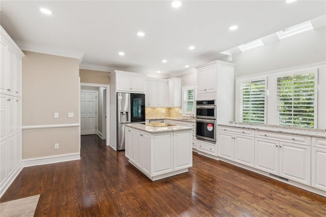 kitchen with appliances with stainless steel finishes, crown molding, white cabinets, a kitchen island, and a sink