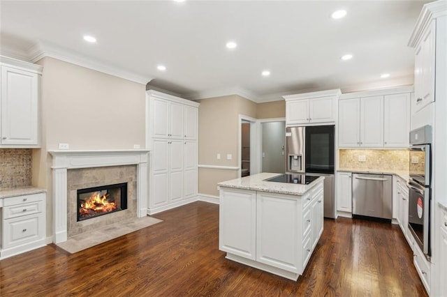 kitchen with stainless steel appliances, white cabinets, a center island, decorative backsplash, and recessed lighting