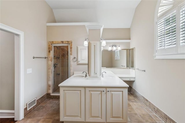 bathroom featuring a shower stall, healthy amount of natural light, baseboards, vaulted ceiling, and double vanity