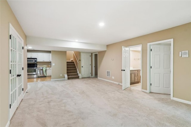 unfurnished living room featuring light colored carpet, stairway, baseboards, and recessed lighting
