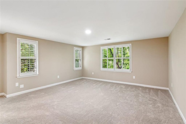 empty room featuring carpet, baseboards, and healthy amount of natural light