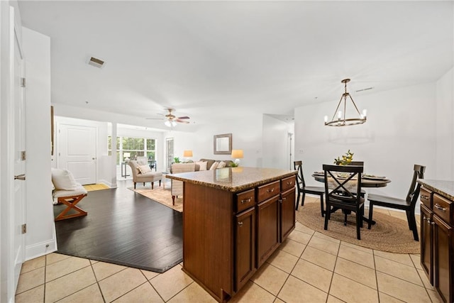 kitchen with visible vents, pendant lighting, ceiling fan with notable chandelier, dark brown cabinetry, and light tile patterned floors