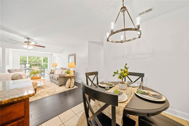 dining room with light tile patterned floors, visible vents, ceiling fan with notable chandelier, and baseboards