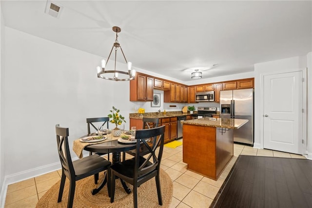 kitchen with light tile patterned floors, visible vents, stainless steel appliances, a notable chandelier, and a center island