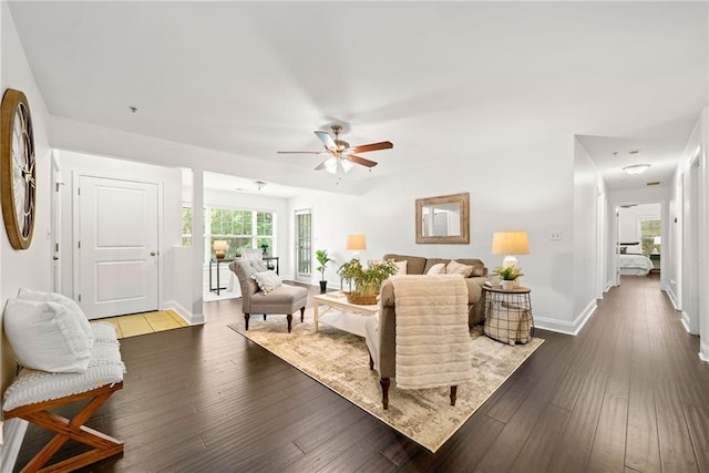 living room featuring dark wood finished floors, baseboards, and ceiling fan