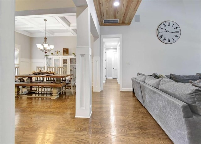 interior space with visible vents, wood finished floors, beamed ceiling, a notable chandelier, and coffered ceiling