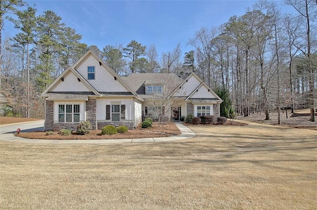 craftsman-style home with a front yard and stone siding