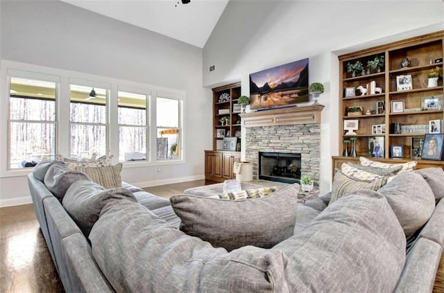 living area featuring baseboards, a fireplace, high vaulted ceiling, and wood finished floors