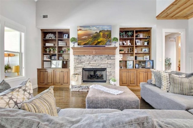 living area featuring a high ceiling, visible vents, wood finished floors, and a fireplace