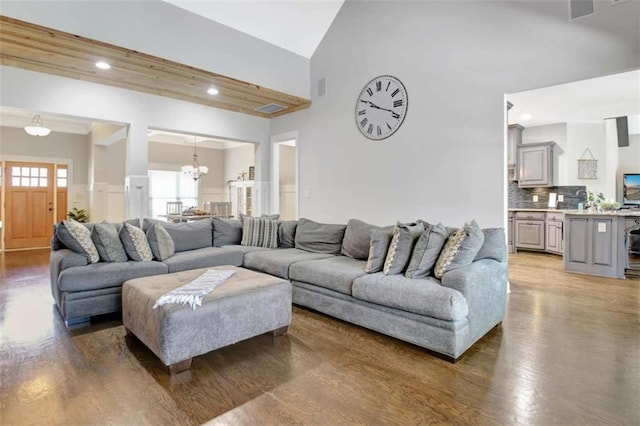 living area with recessed lighting, wood finished floors, a notable chandelier, and high vaulted ceiling