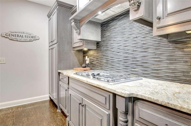 kitchen featuring tasteful backsplash, stainless steel gas cooktop, gray cabinets, baseboards, and dark wood-type flooring