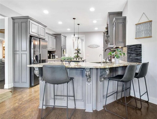 kitchen featuring gray cabinetry, light stone counters, a peninsula, stainless steel fridge, and recessed lighting