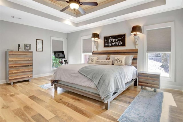 bedroom with crown molding, a raised ceiling, baseboards, and visible vents