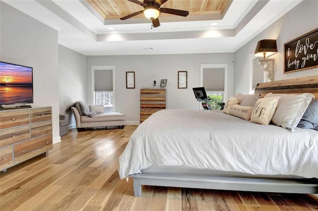 bedroom with crown molding, wood finished floors, baseboards, recessed lighting, and a tray ceiling