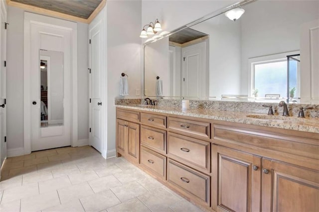 full bathroom with a sink, baseboards, tile patterned flooring, and double vanity