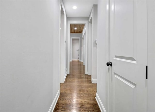 corridor featuring baseboards and dark wood-style flooring