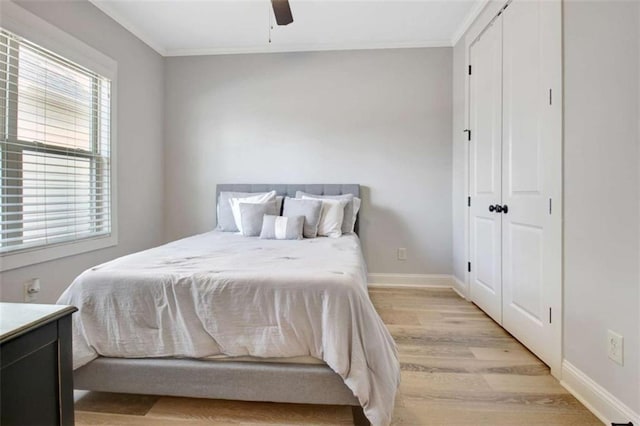 bedroom with baseboards, a ceiling fan, light wood-style flooring, and crown molding