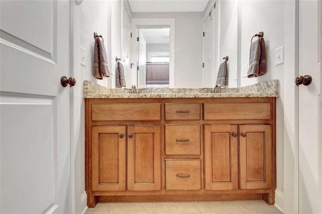 bathroom featuring double vanity, baseboards, tile patterned floors, and a sink