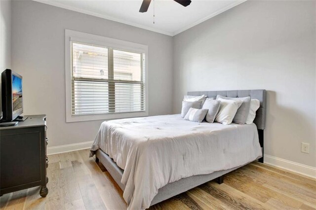 bedroom with a ceiling fan, baseboards, ornamental molding, and light wood-style flooring