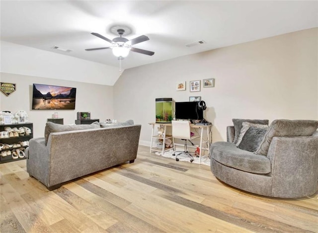 living area with light wood-style floors, a ceiling fan, visible vents, and vaulted ceiling