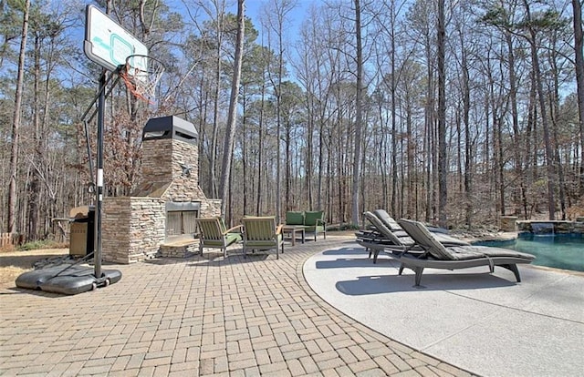 view of patio with an outdoor stone fireplace and a pool