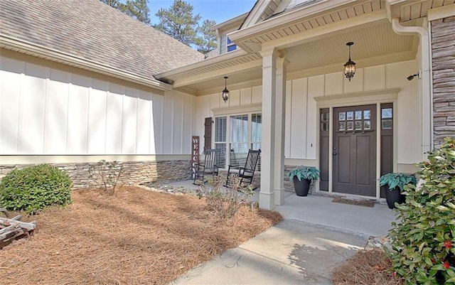 doorway to property with board and batten siding, roof with shingles, and a porch