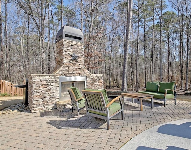 view of patio / terrace featuring fence and an outdoor living space with a fireplace