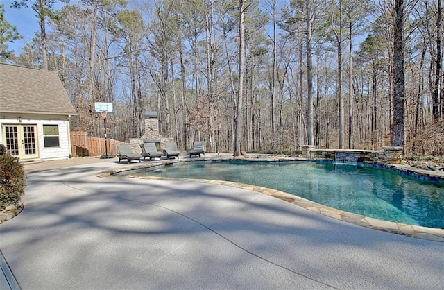 pool with french doors, fence, and a patio area