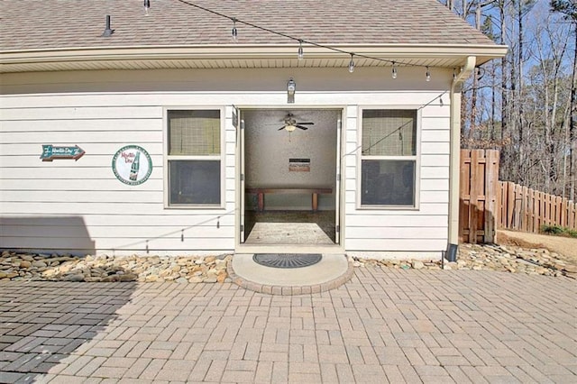 entrance to property featuring fence and roof with shingles