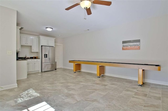 interior space featuring dark countertops, a ceiling fan, white cabinetry, baseboards, and stainless steel refrigerator with ice dispenser